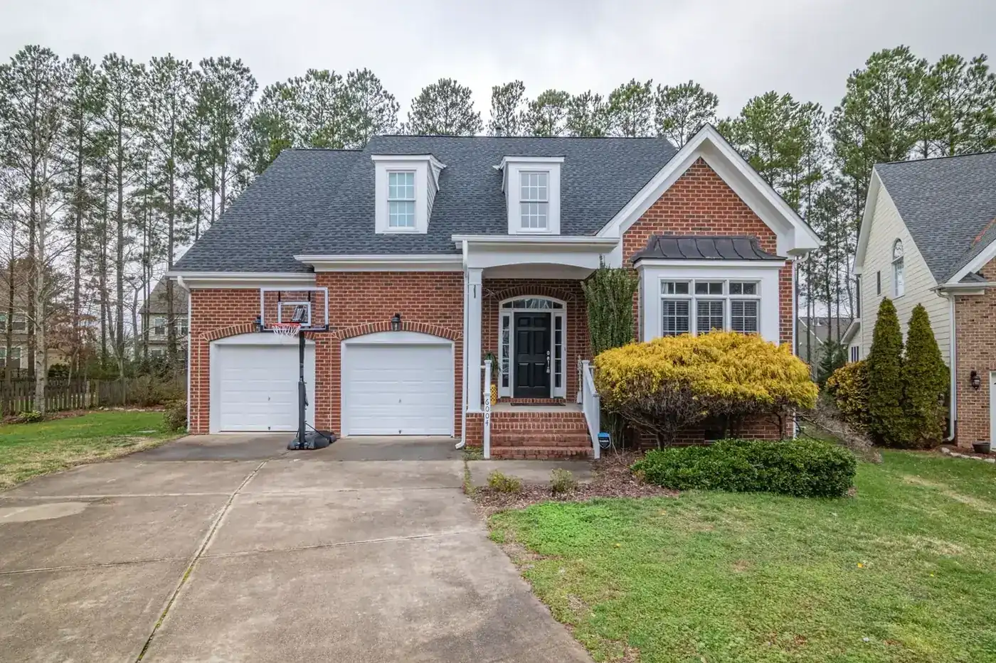 A brick suburban home with an attached garage on a quiet street